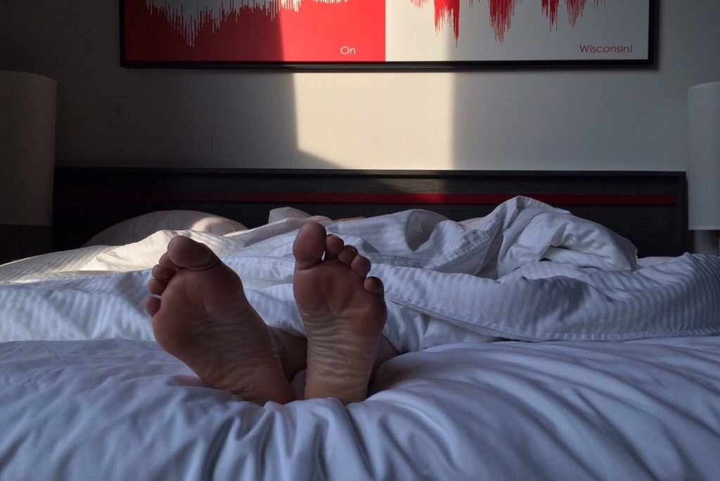 Person som sover i en säng. Enbart fötterna syns.