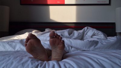 Person som sover i en säng. Enbart fötterna syns.