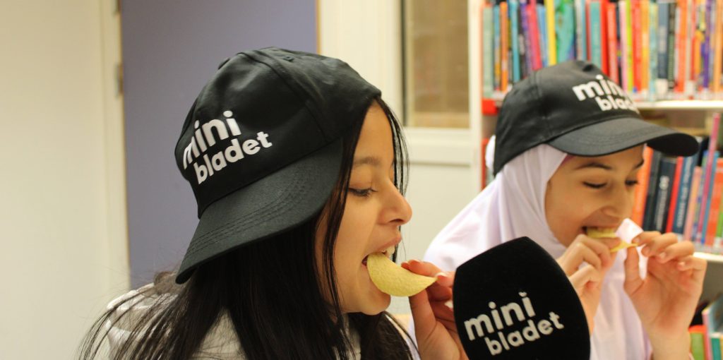 Två minireportrar i närbild knaprar på chips.